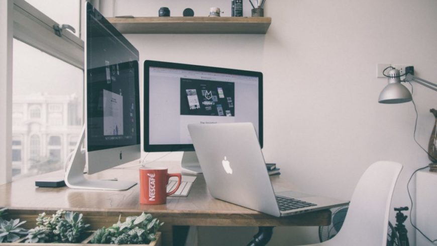 Remote working workspace with coffee, computers, and greenery