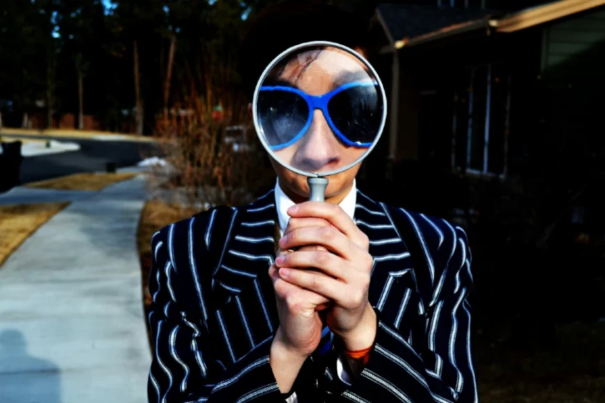 Photo of a man with sunglasses looking through a magnifying glass as a metaphore for Search Engine Optimisation by Marten Newhall on Unsplash