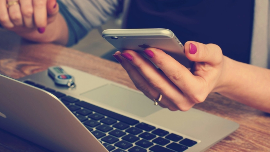 Photo of laptop and someone holding a mobile phone by Firmbee.com on Unsplash